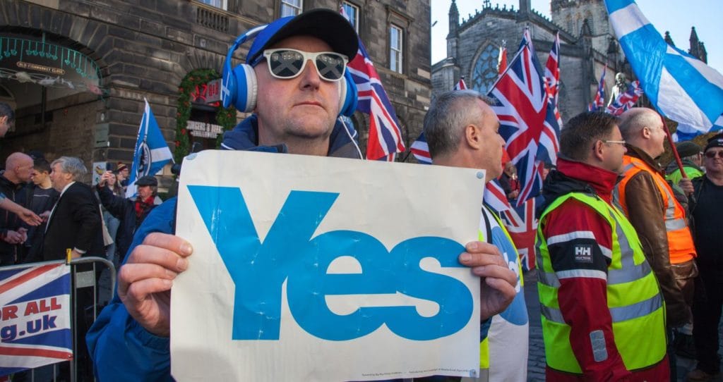 Activist holding a Yes sign in front of UK counter-demonstration