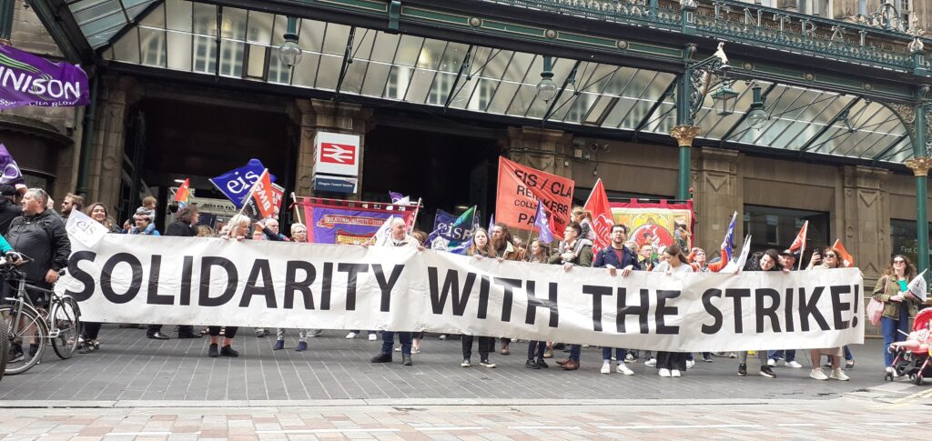 Workers on strike with a large banner reading "solidarity with the strike"